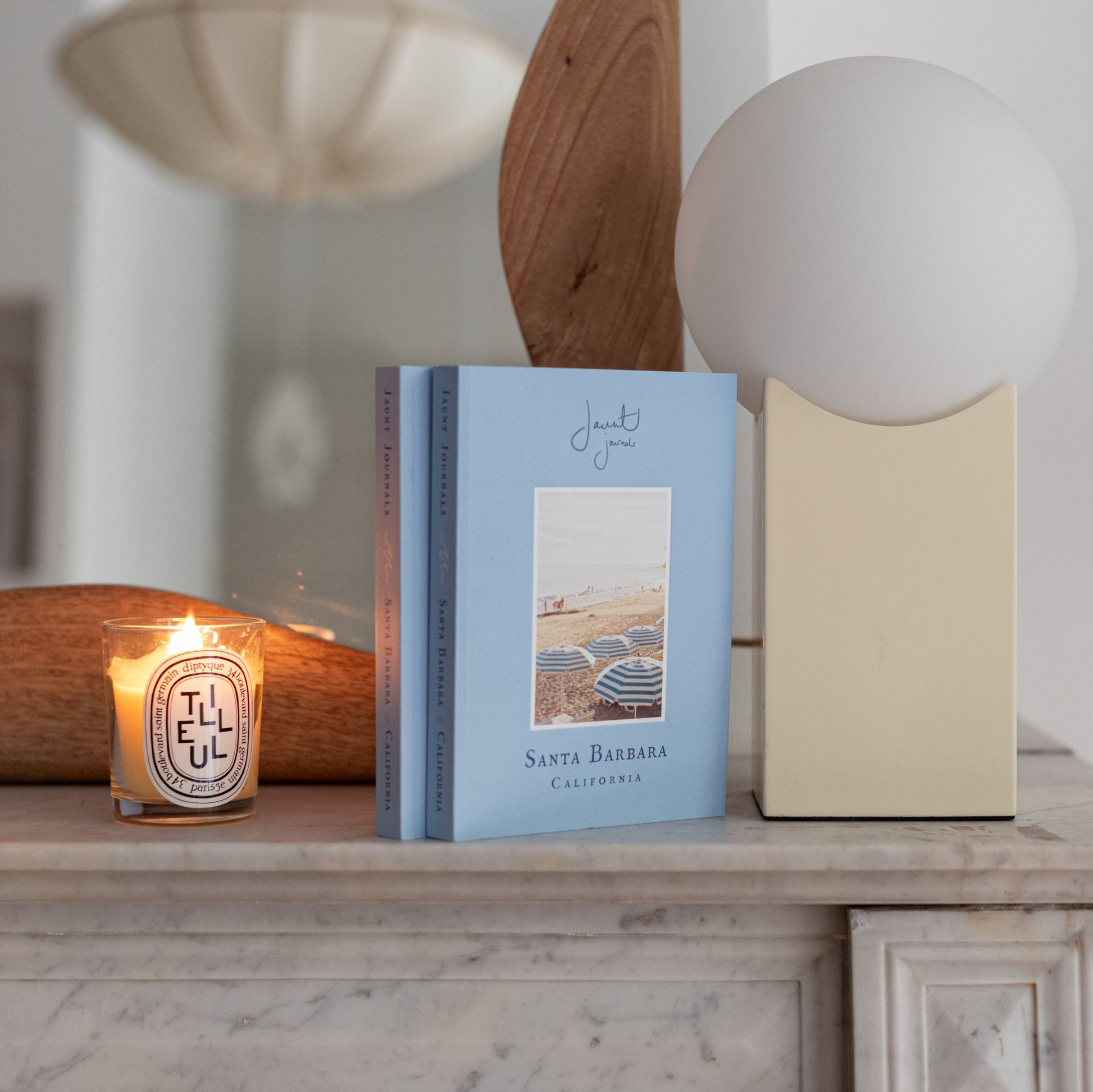Picture of the book, Jaunt Jouranls Santa Barbara on a fireplace with a candle burning