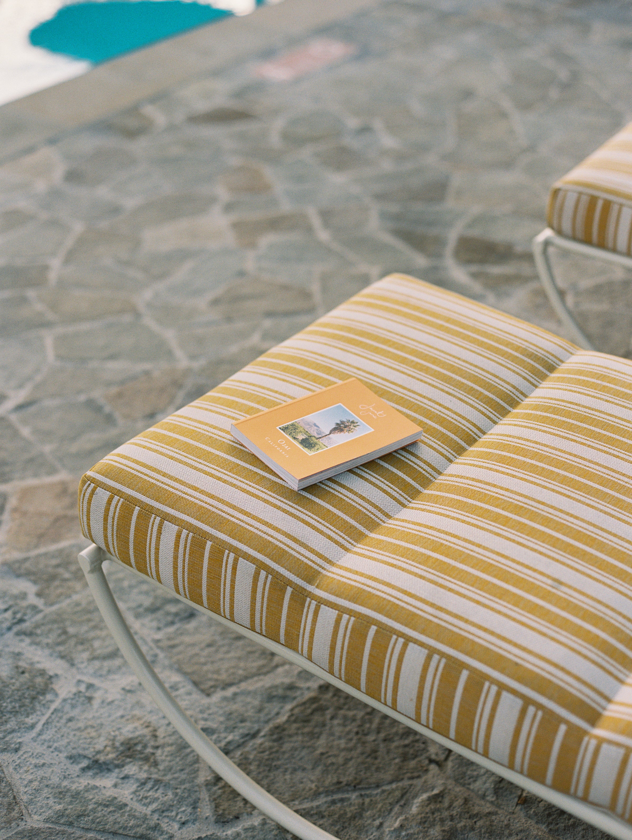 Yellow and white striped cushion on a chair with a stone patio background